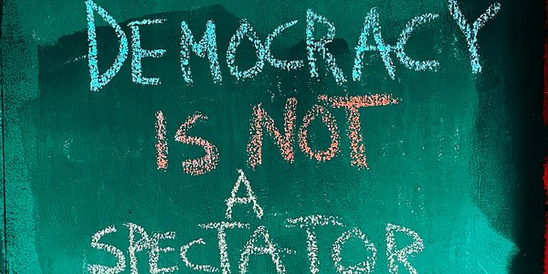 Eine Wand der in English steht seht: "Demokratie ist kein Zuschauersport"