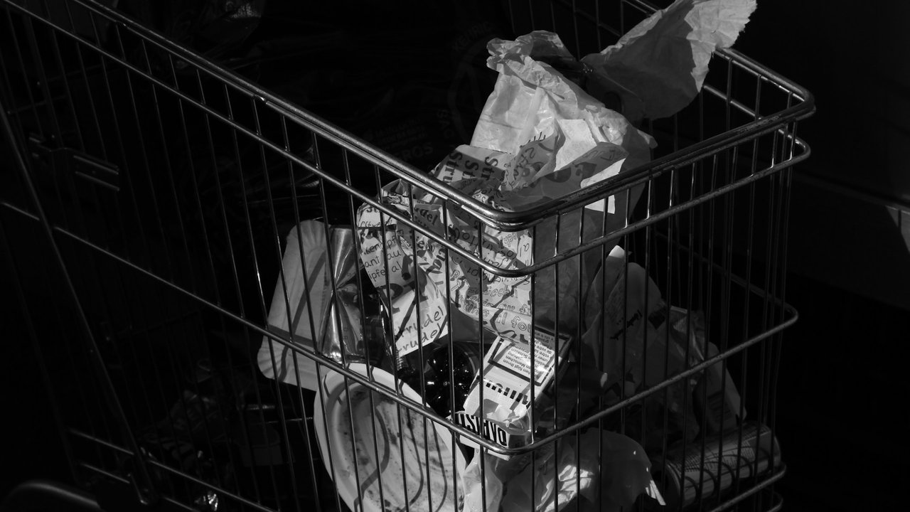 Schwarzweiß Bild eines Einkaufswagens mit Müll