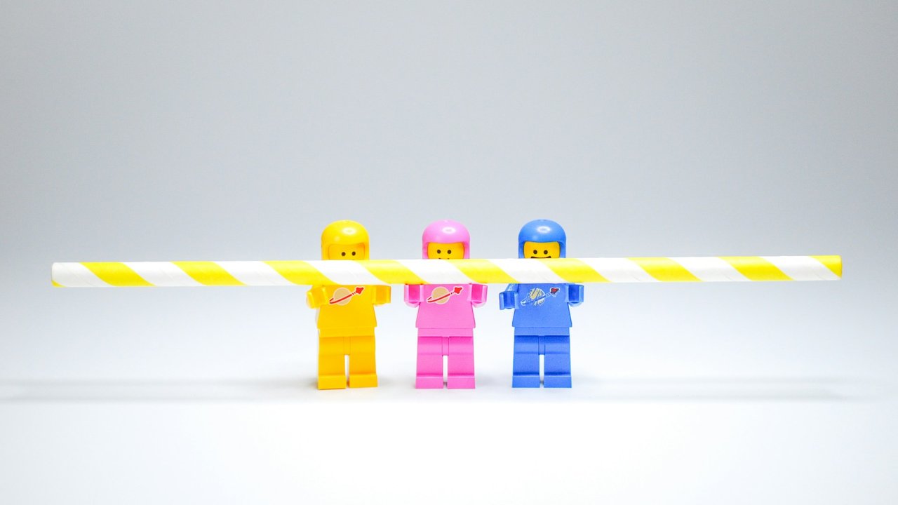 Drei Legofiguren halten einen Strohalm
